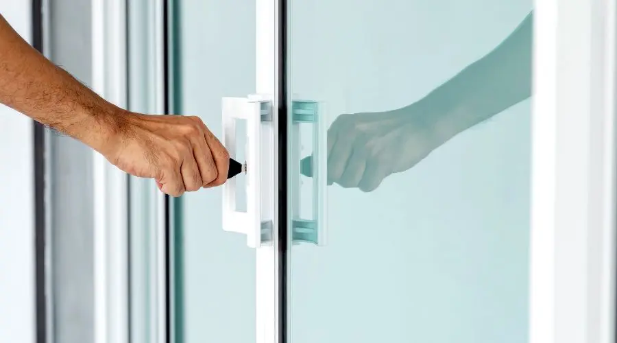 Main qui ferme une porte-patio de fabricant de portes et fenêtres